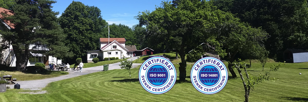 ISO-certifikat ISO-9001 och ISO-14001. I bakgrunden syns Aleforshemmet, Aleforsstiftelsens behandlingshem.